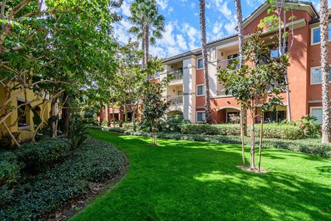 A green lawn in front of a building with trees.
